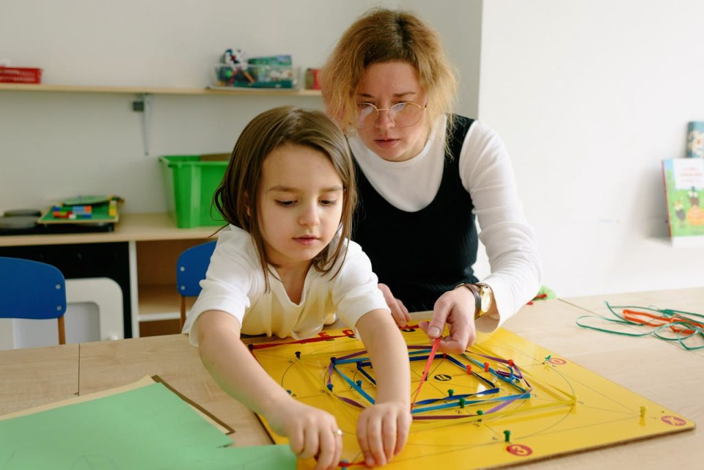A child and teacher work together on an educational activity in a classroom setting.